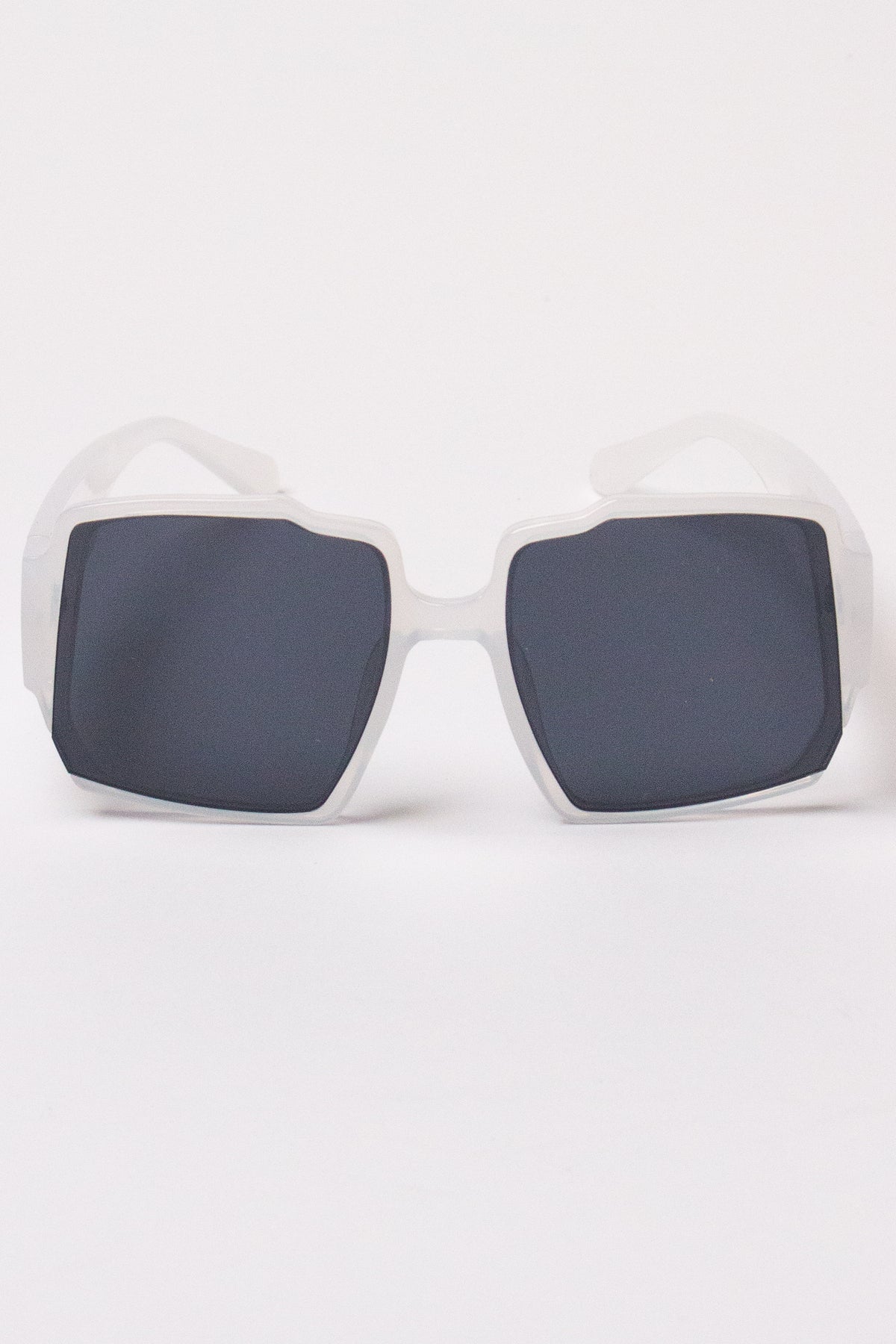 Oversized geometric sunglasses with frosted white frames and dark tinted lenses