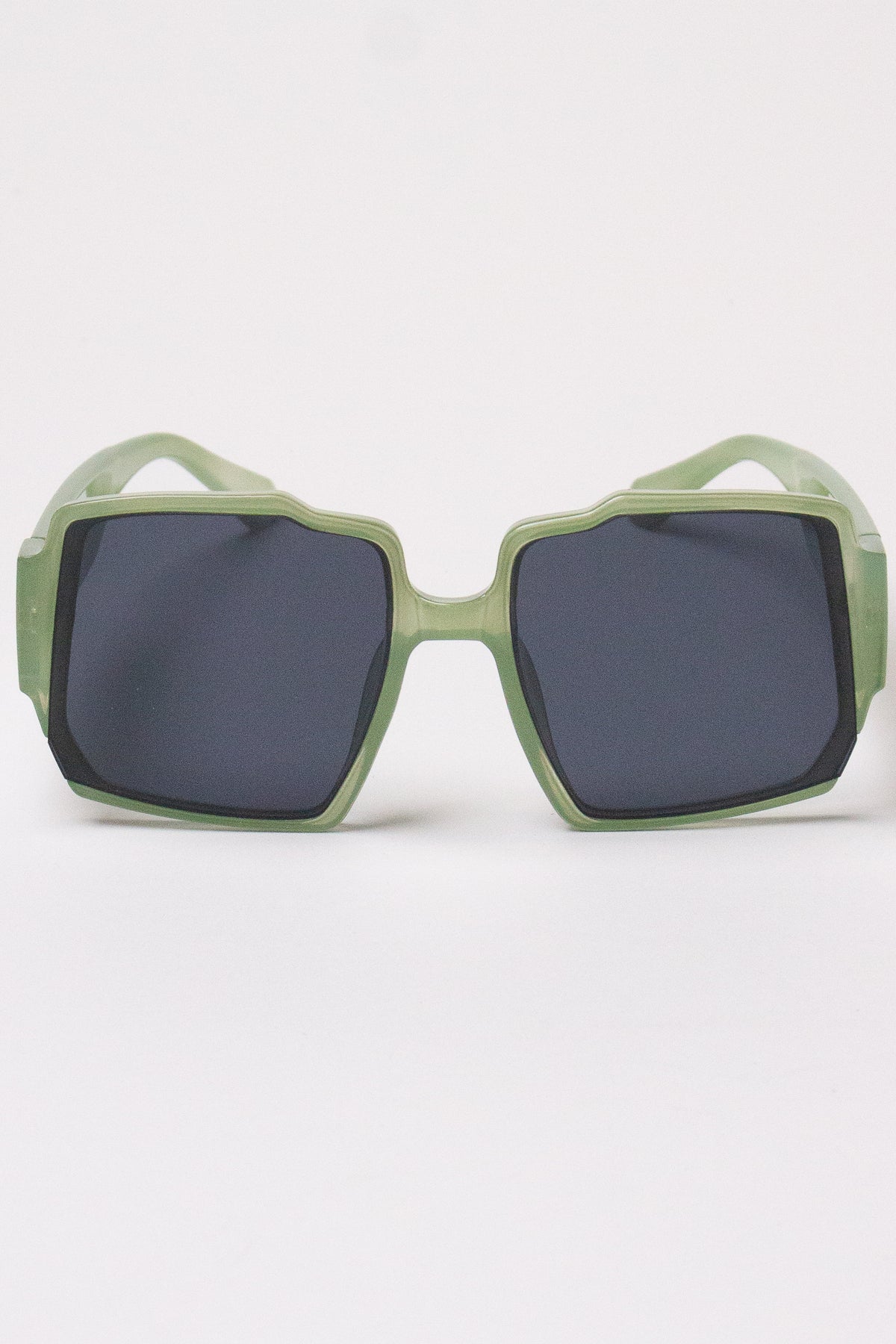 Oversized geometric sunglasses with translucent sage green frames and dark tinted lenses