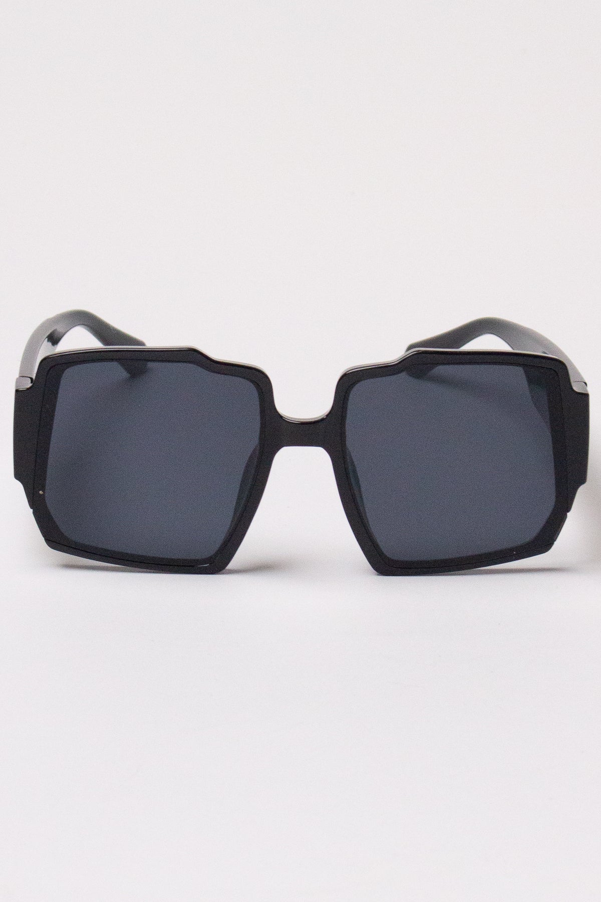 Oversized black geometric sunglasses with notched square frames and dark lenses