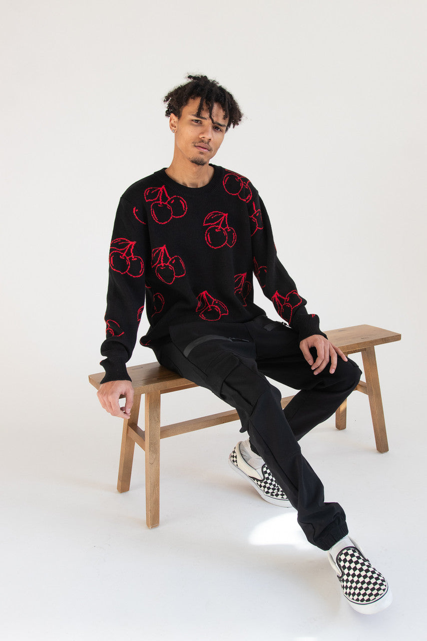 Man wearing black sweater with red cherry pattern