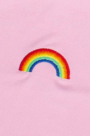 Close-up of embroidered rainbow design on soft pink fabric of baby tee shirt