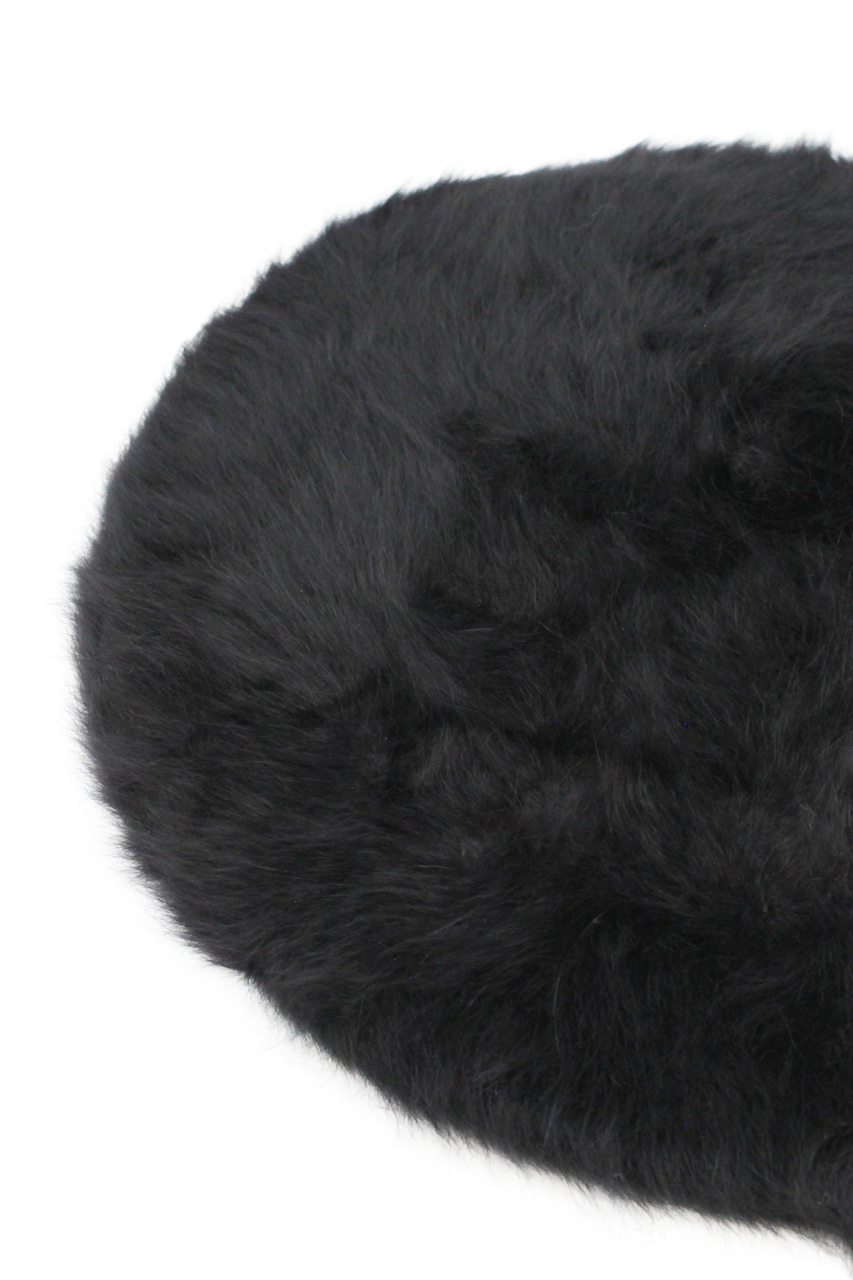 Round black fluffy faux fur cushion on a white background