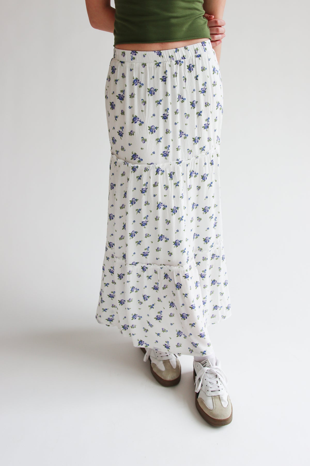 White tiered maxi skirt with small blue rose pattern and elastic waistband worn with casual sneakers