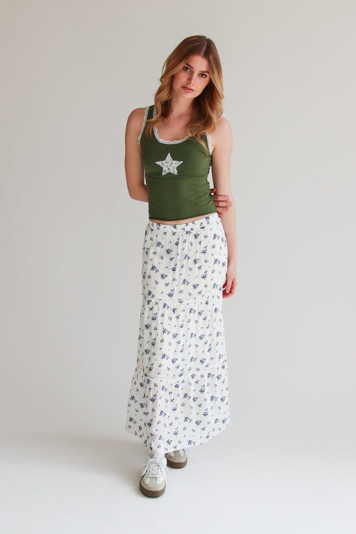 Woman wearing a white rose pattern tiered maxi skirt with elastic waistband and casual green tank top.