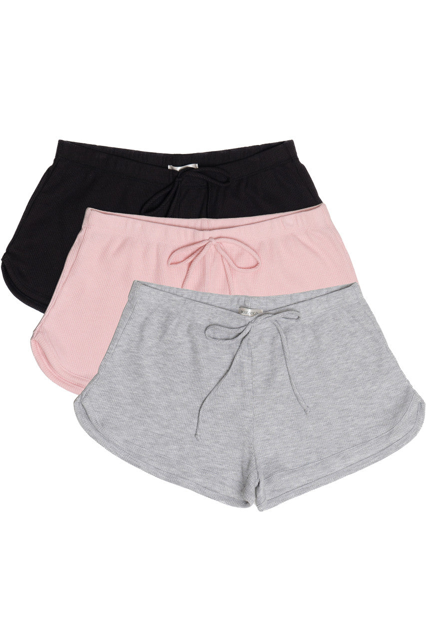 Three pairs of Thermal Dolphin Shorts in black, pink, and grey with drawstring waistbands on white background