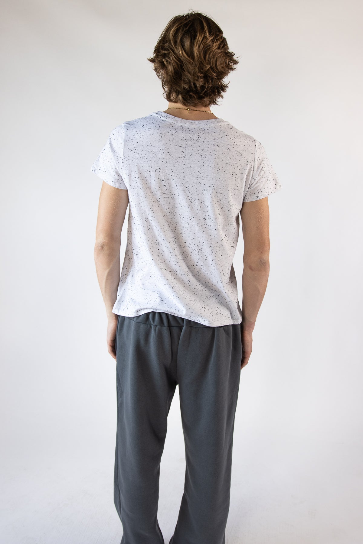 Back view of a man wearing a white speckled short-sleeve t-shirt and charcoal sweatpants