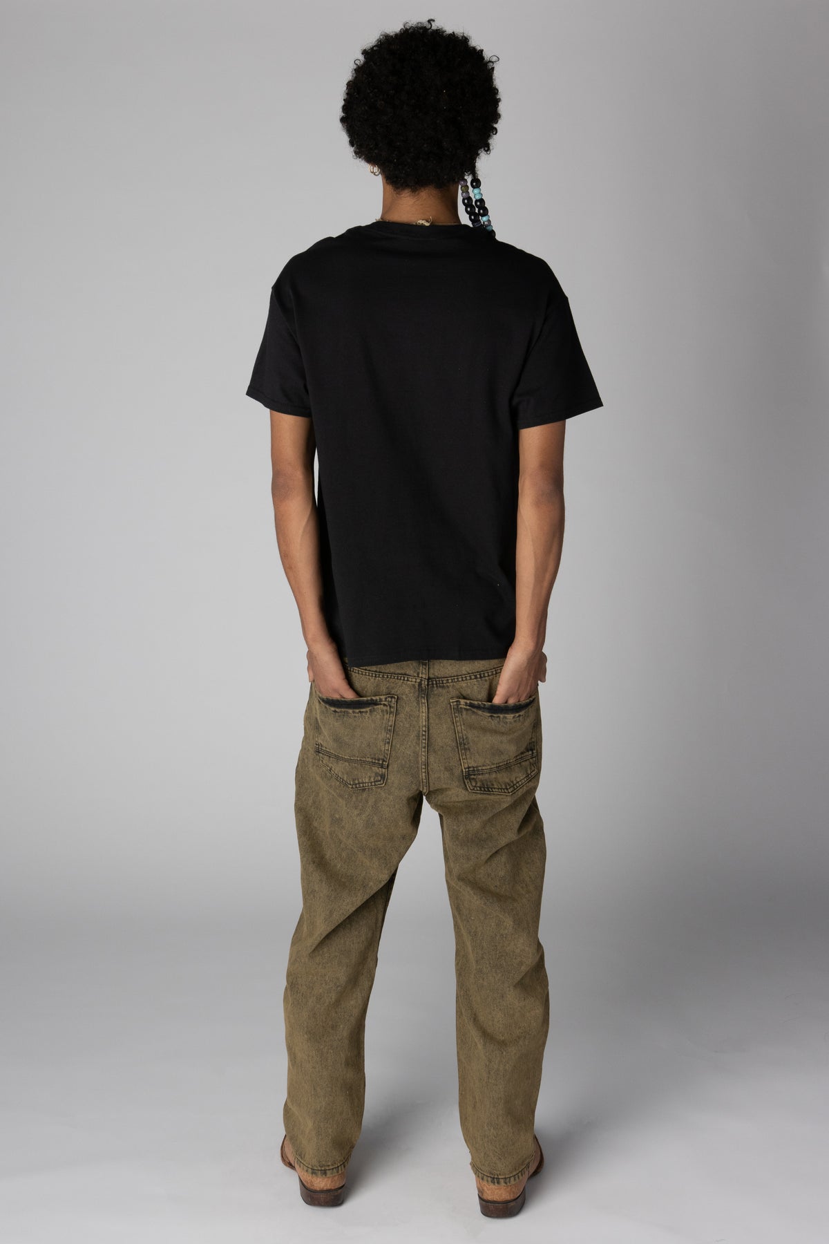 Back view of model wearing a plain black t-shirt and acid-washed relaxed fit jeans