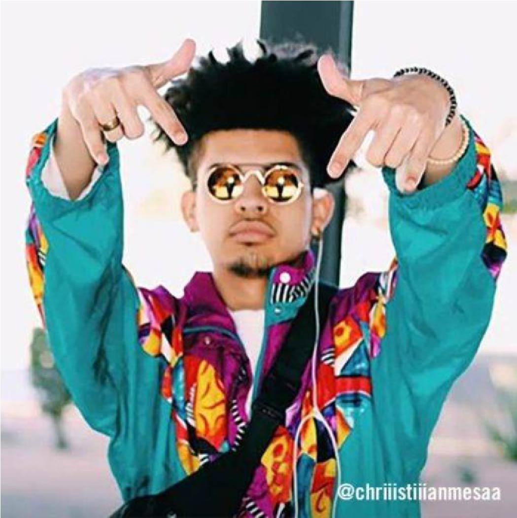 @chriiistiiianmesaa pointing to the camera in a bold neon windbreaker and gold shades.
