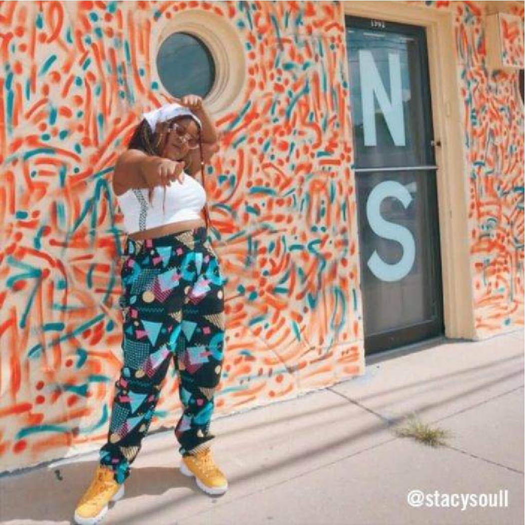 @stacysoull in colorful high-waisted patterned pants outside a mural–retro 90's street style.