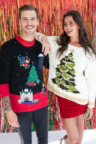 Man and woman wearing colorful vintage ugly Christmas sweaters posing in front of red and gold tinsel backdrop