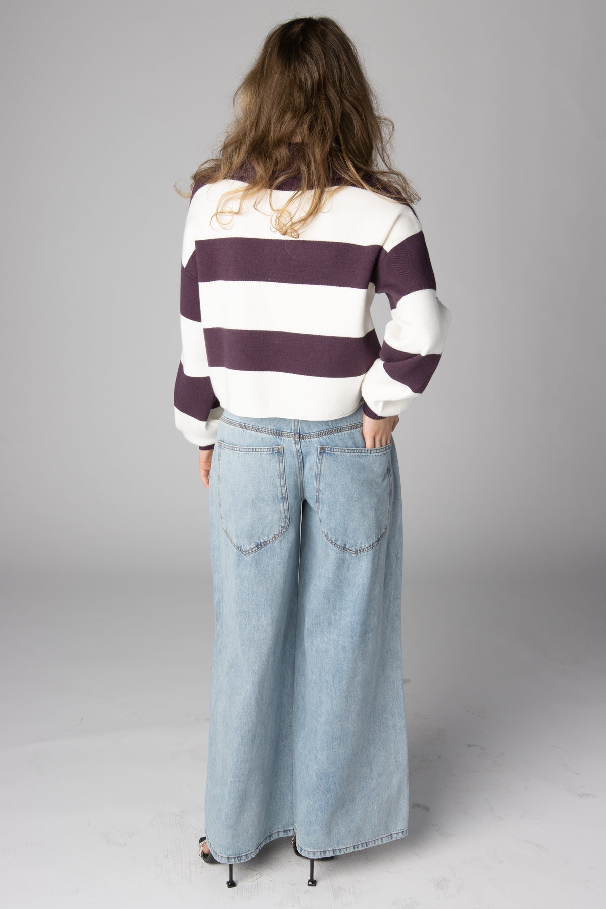 Model from behind wearing a purple and white striped sweater and light-wash wide-leg