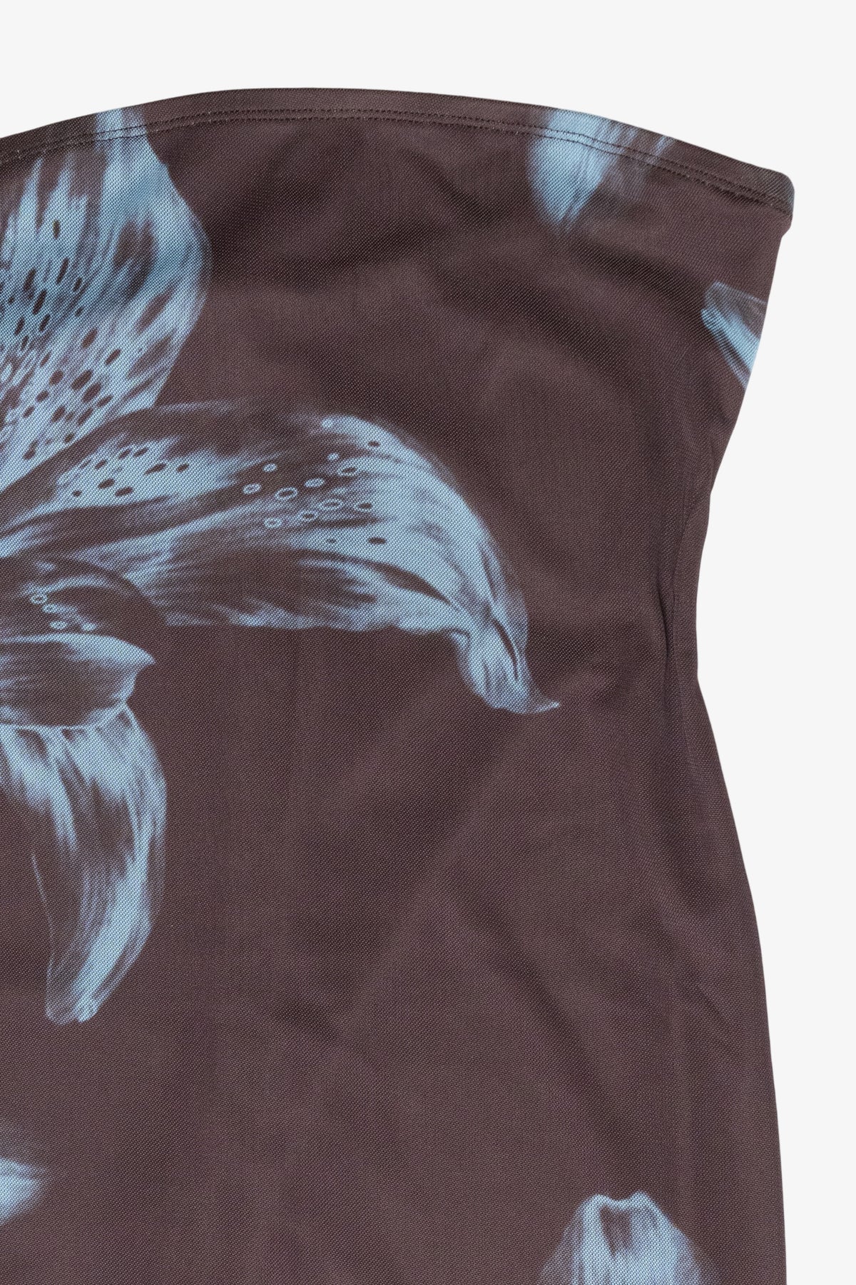 Close-up of a dark brown strapless top or dress featuring a large white and light blue lily floral print, shown against a plain light background.