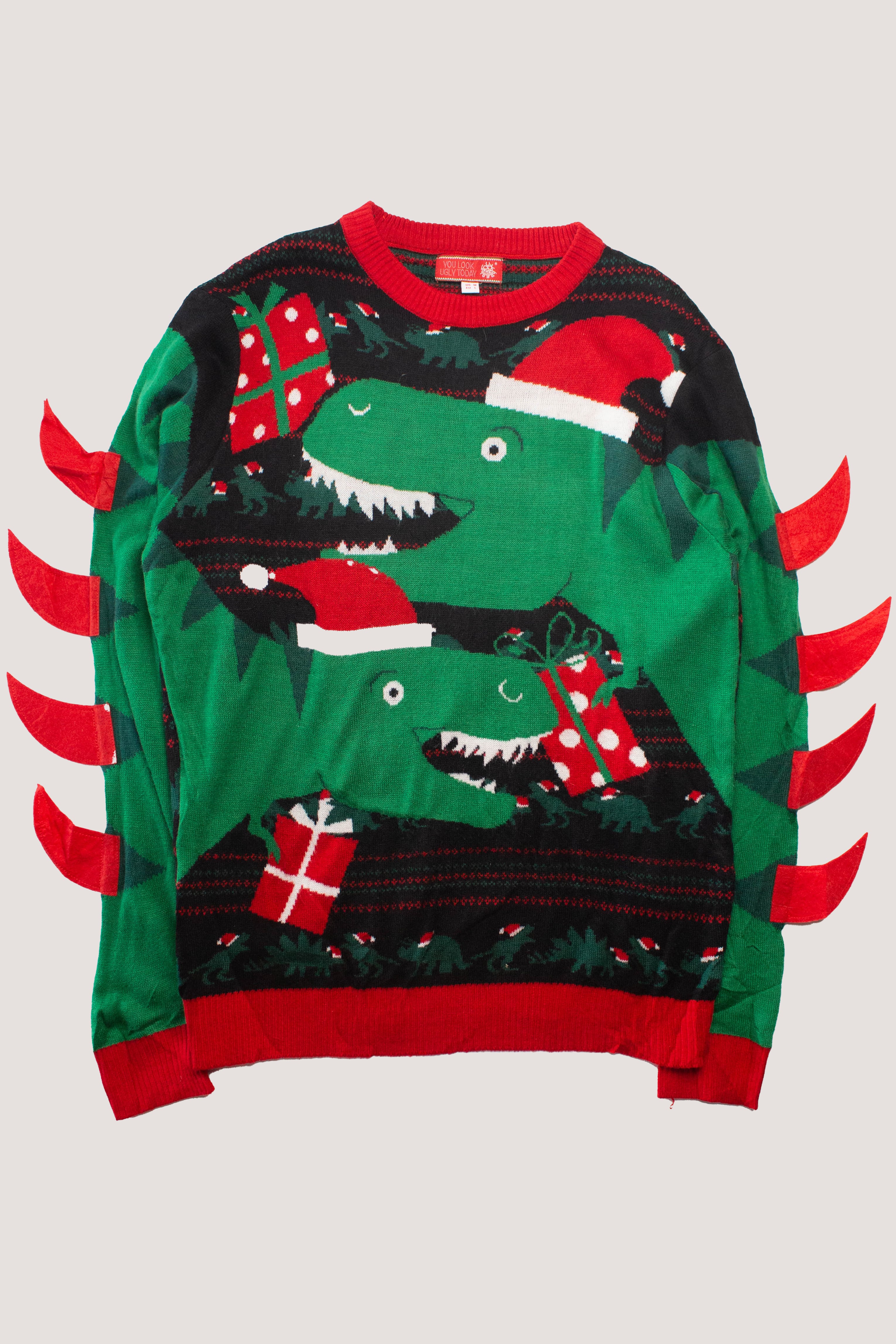 Green Christmas sweater with two dinosaurs in Santa hats holding presents and red fabric spikes on sleeves.