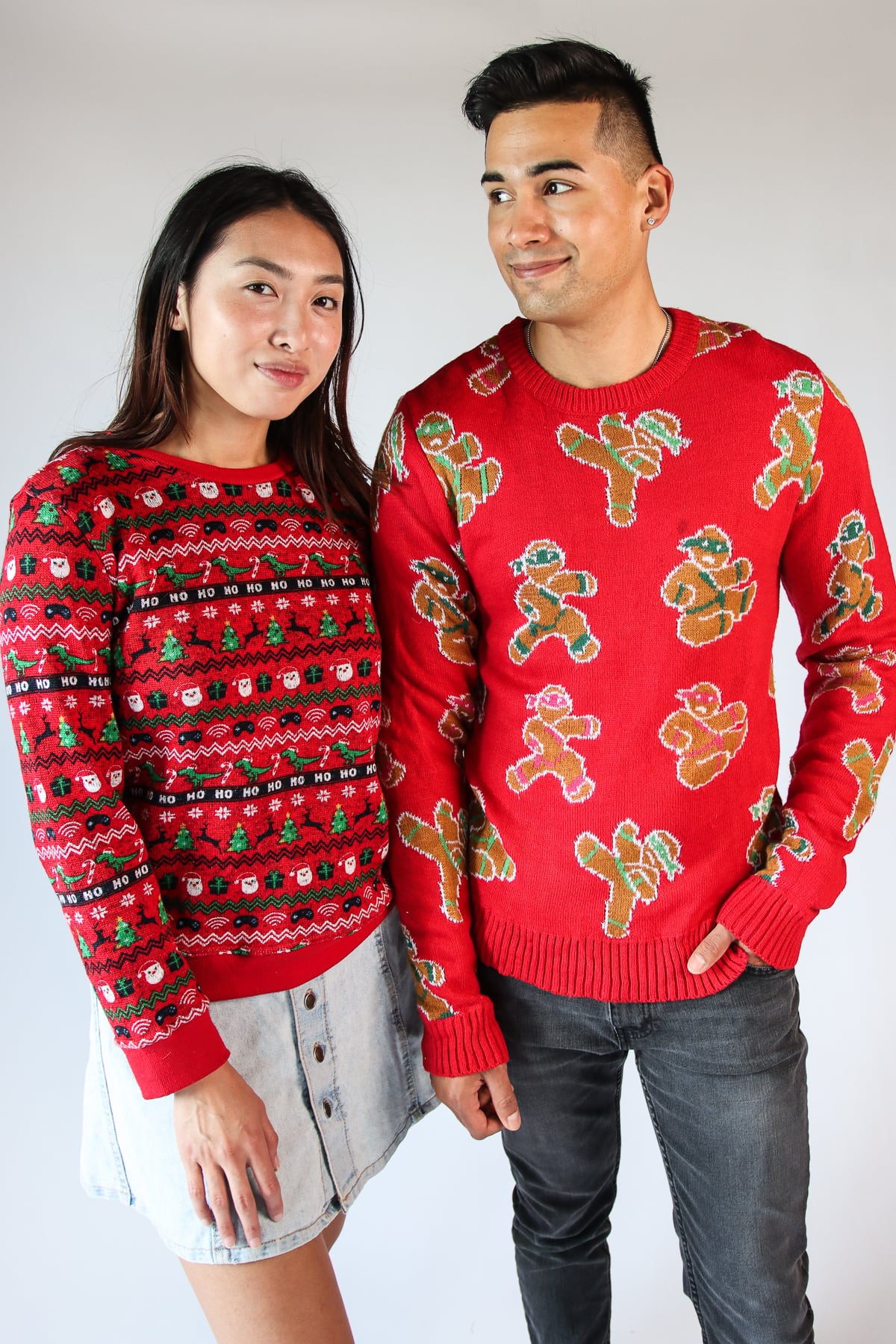 Woman and man wearing red modern ugly Christmas sweaters with festive holiday patterns standing together