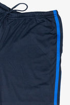Close-up of navy athletic pants featuring an elastic drawstring waistband and a bright blue side stripe