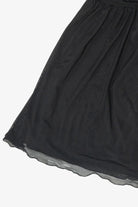 Close-up of the gathered hem on a black sheer mesh dress
