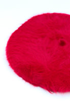 Bright red fuzzy angora beret hat on white background