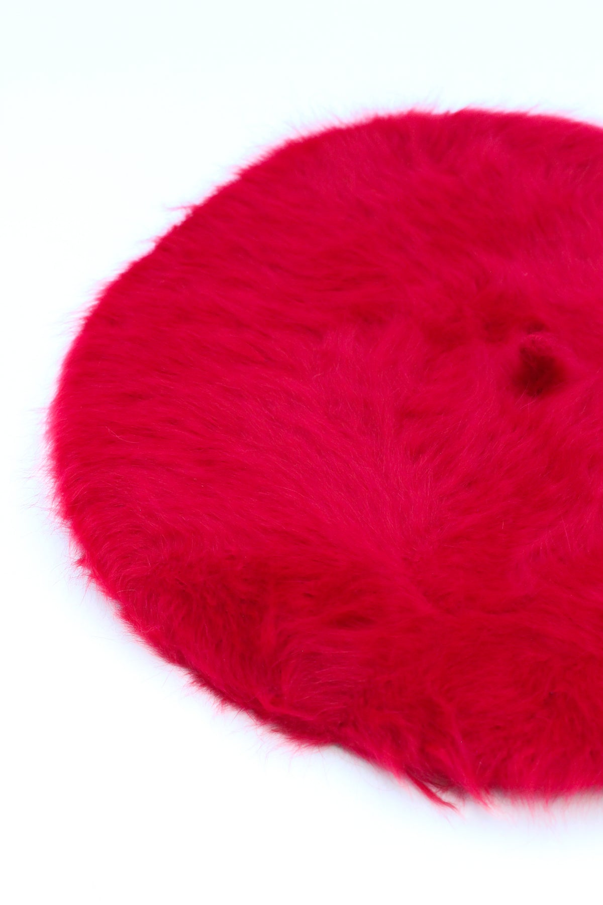 Bright red fuzzy angora beret hat on white background