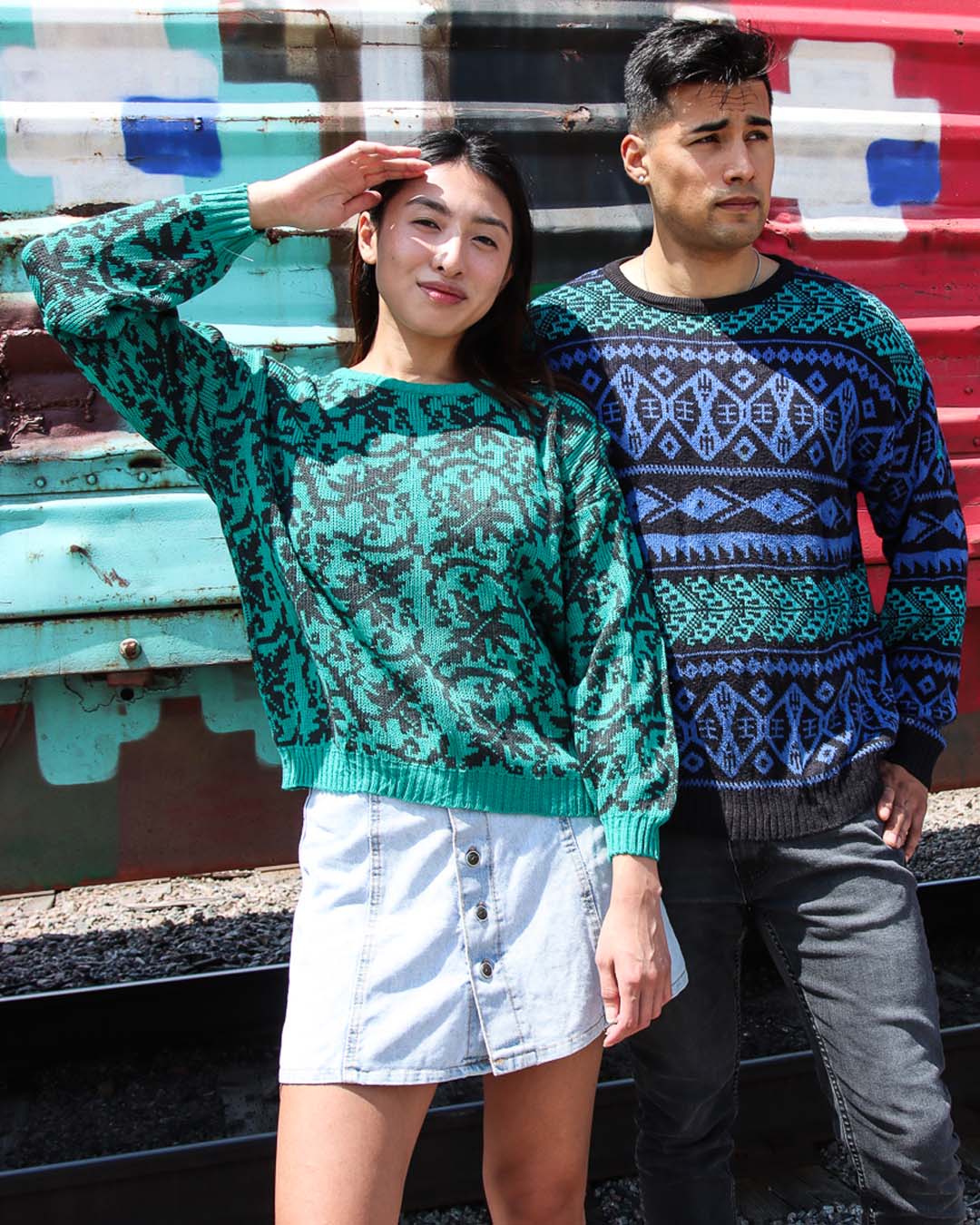 Models wearing 80s vintage sweaters in front of a colorful background