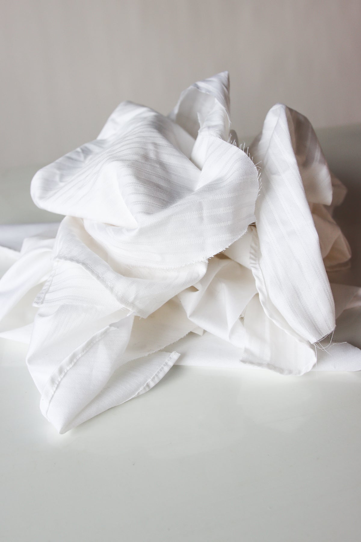 Piled assortment of mixed light weight white fabric wiping cloths