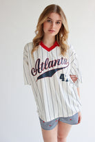 Woman wearing an oversized collared jersey with Atlanta text and number 44 in white with pinstripes and red collar