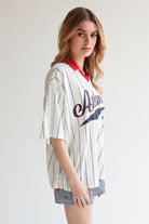 Woman wearing an oversized white collared jersey with black stripes and red collar, paired with patterned shorts