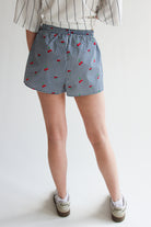 Rear view of person wearing printed gingham boxer shorts with cherry patterns and elastic waistband