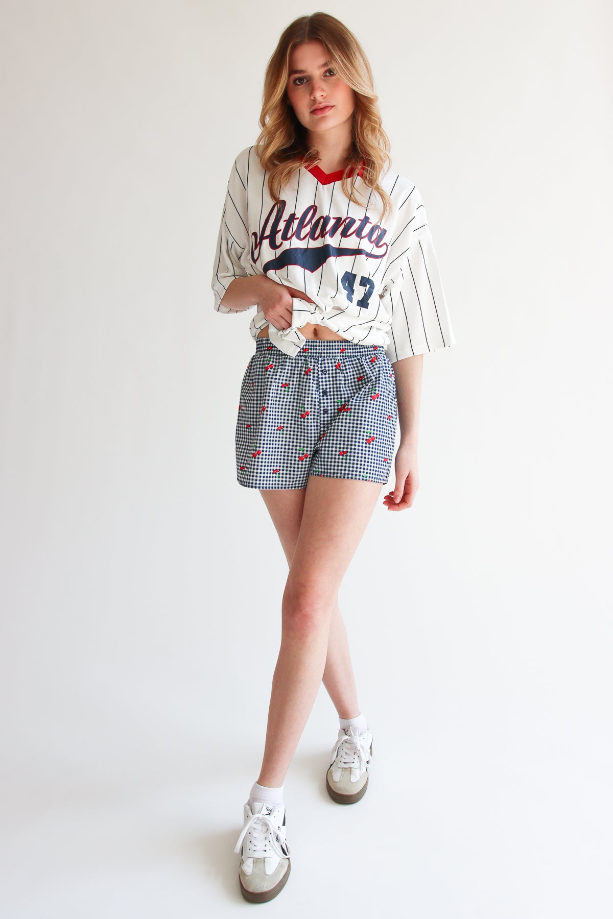 Young woman wearing printed gingham boxer shorts with elastic waistband and a casual baseball tee