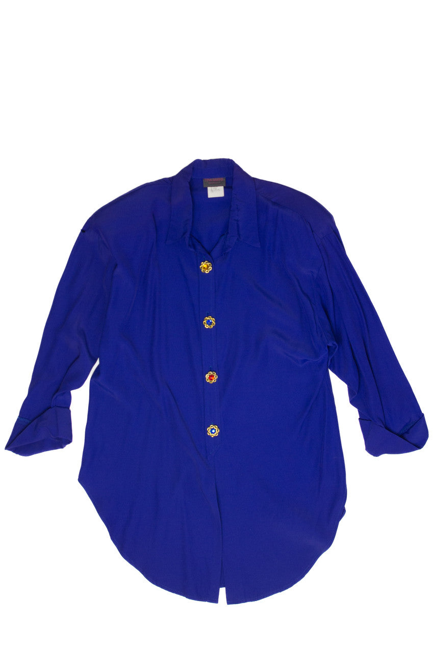 Vintage 1980s Tina Barrie blue top with shoulder pads and colorful decorative buttons laid flat