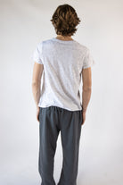 Back view of a man wearing a white speckled short-sleeve t-shirt and charcoal sweatpants