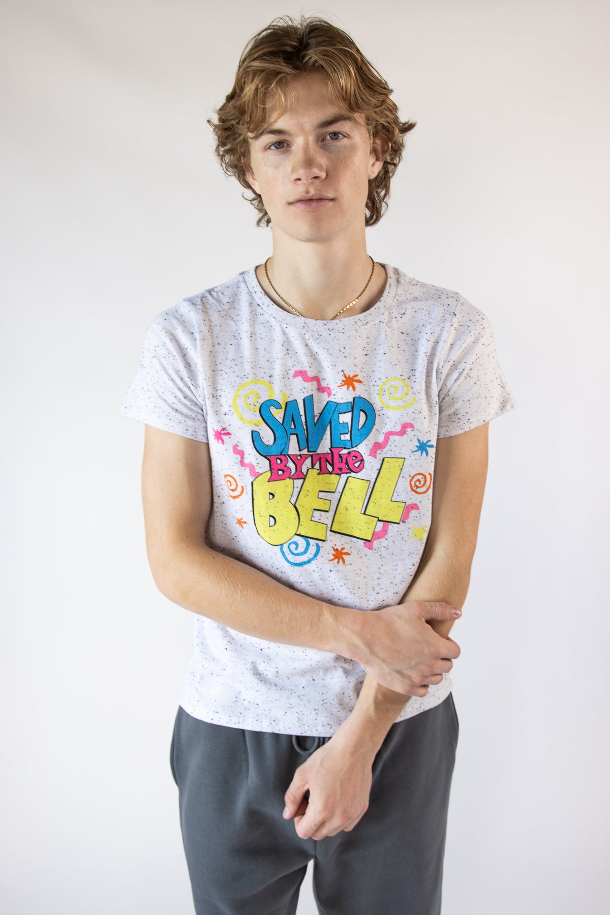 Man wearing a white speckled graphic t-shirt featuring the Saved by the Bell logo