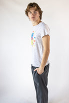 Man wearing a white speckled graphic t-shirt and charcoal sweatpants shown in side profile
