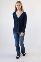 Woman wearing navy blue long-sleeve polka dot V-neck top with blue jeans