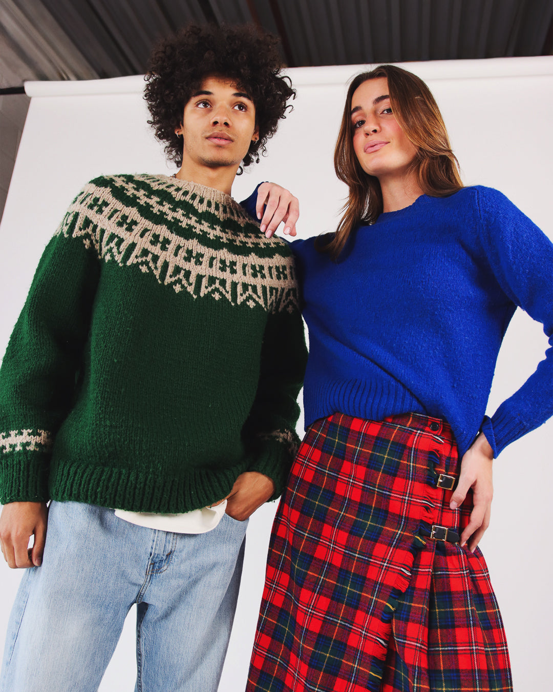 male model wearing vintage green fair isle sweater and female model wearing vintage blue sweater and vintage wool plaid skirt 