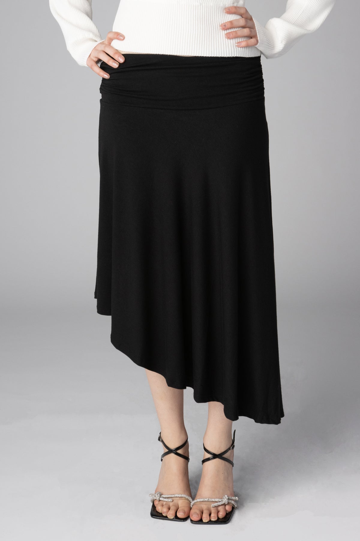 Black draped midi skirt featuring an asymmetrical hemline and wide waistband