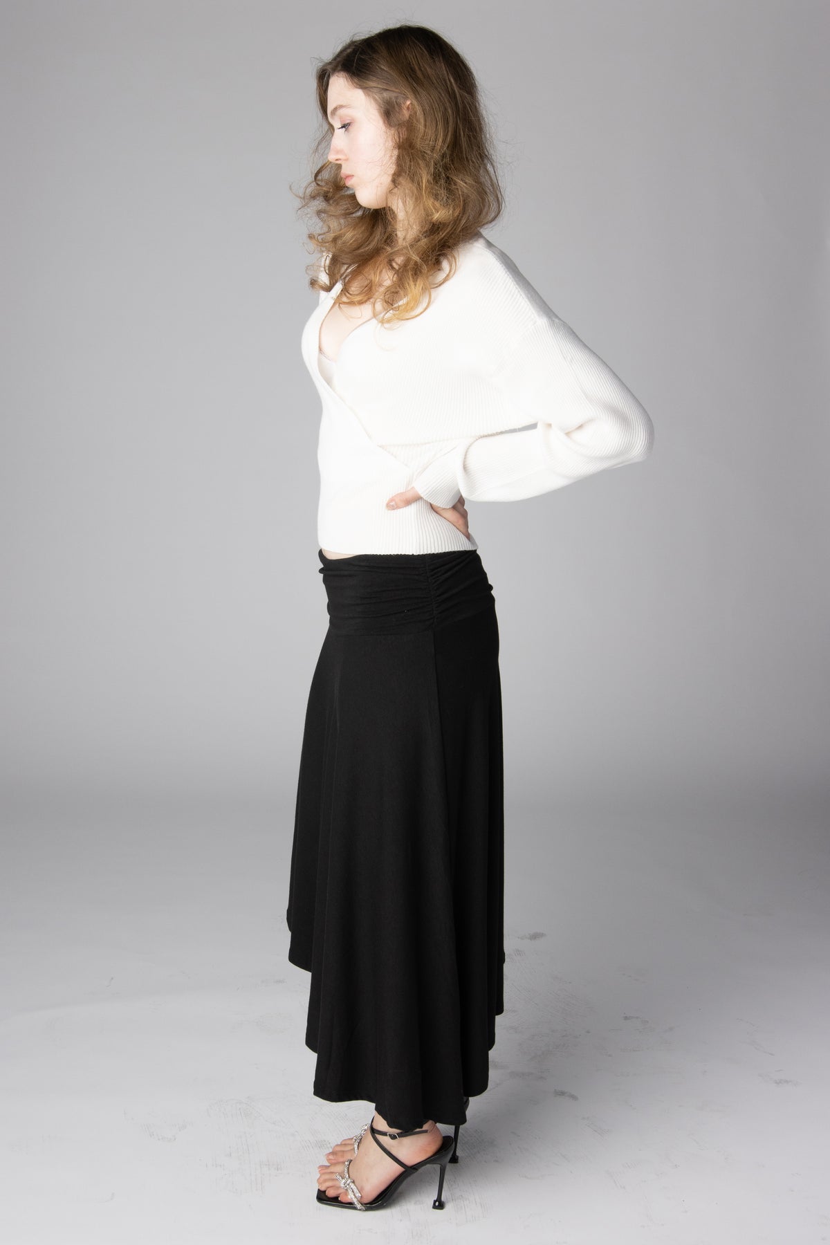 Woman wearing a white long-sleeve knit wrap sweater and a black flowing midi