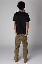 Back view of a person wearing a plain black t-shirt and acid-washed tan denim jeans