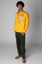 Man wearing a yellow Animaniacs graphic sweatshirt with dark grey jeans