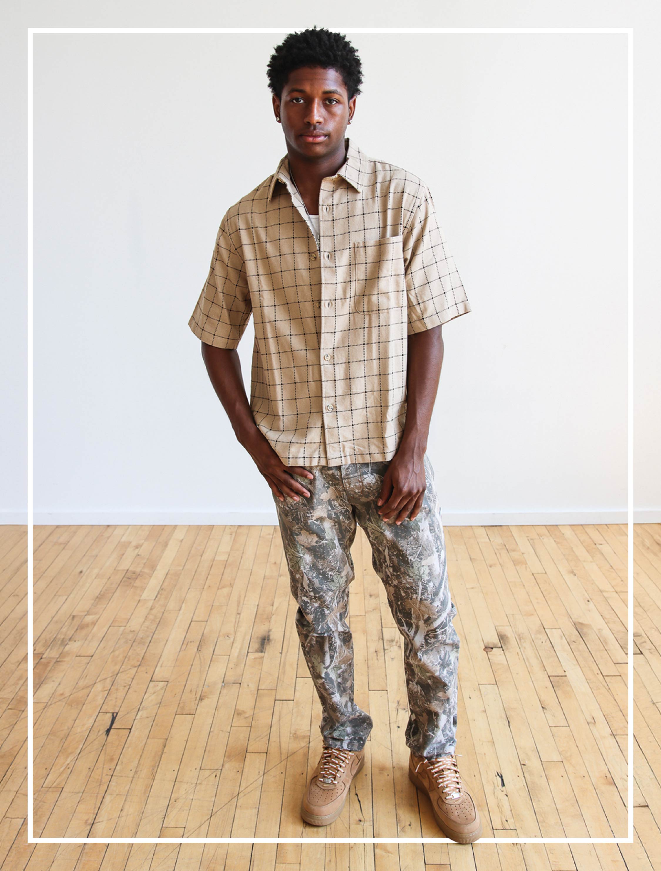 male model wearing checked button-up shirt and camo jeans