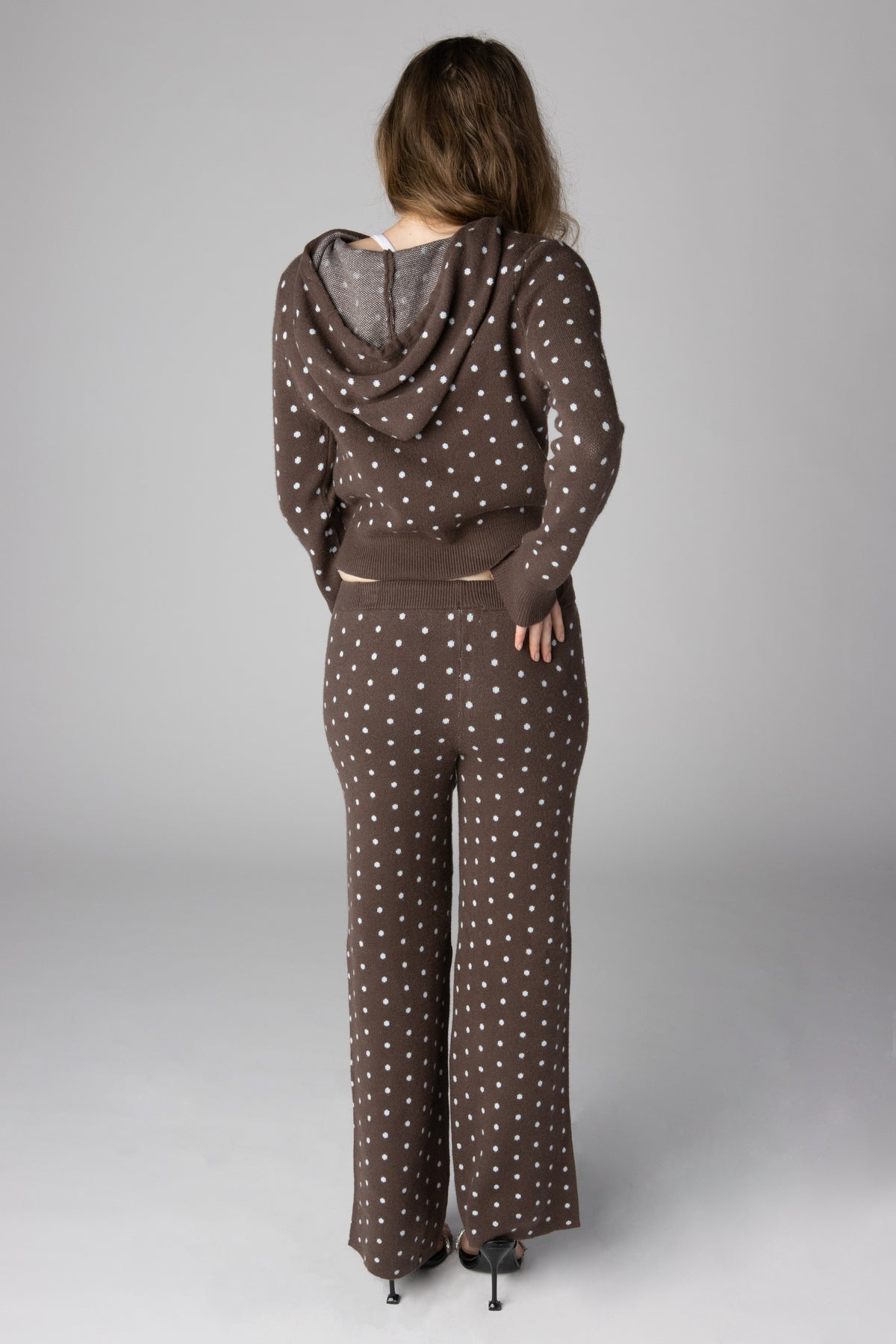 Back view of a woman wearing a brown knit hoodie and wide-leg pants set with white polka dots