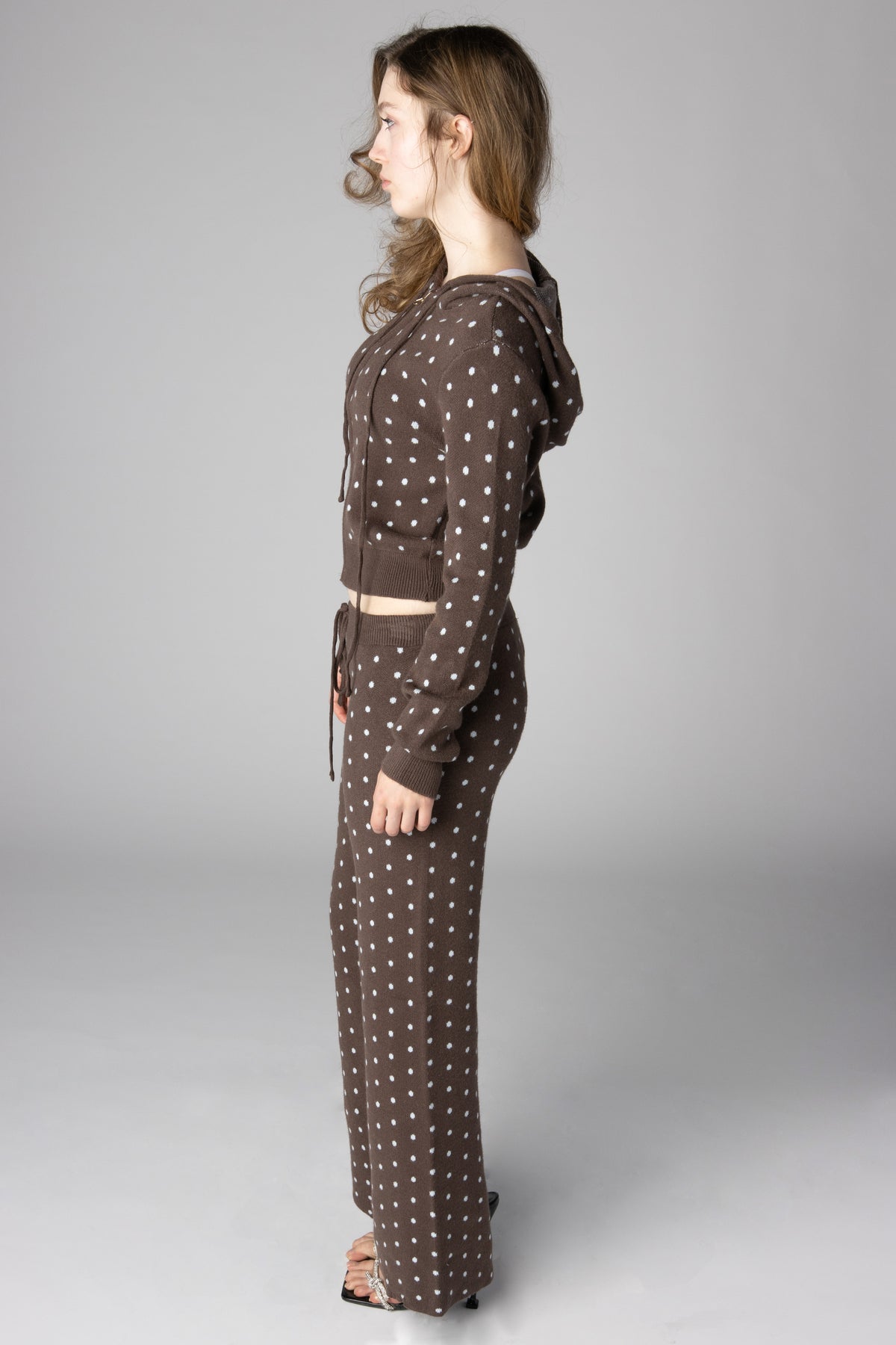 Model wearing a brown and white polka-dot knit cropped hoodie and matching wide-leg lounge pants