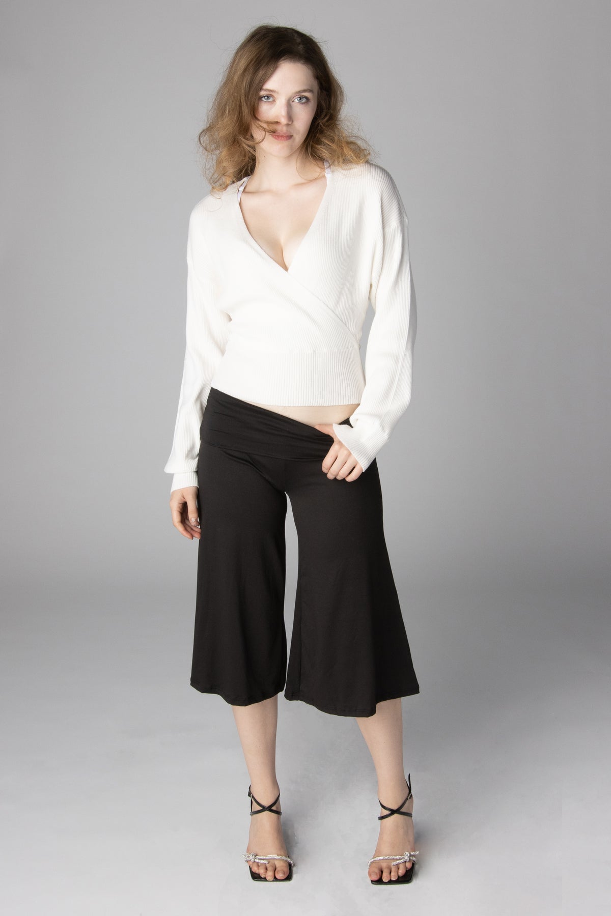 Model wearing a white V-neck wrap sweater and black cropped wide-leg pants