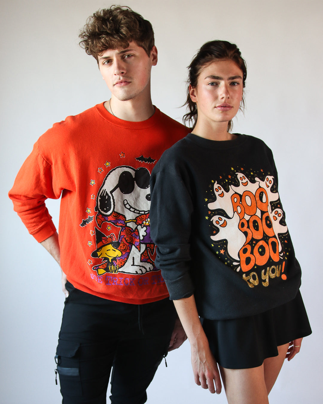 two models wearing vintage halloween sweatshirts. one with ghosts and one with snoopy and woodstock