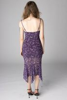 Back view of a purple paisley print midi dress with spaghetti straps and asymmetrical ruffle hem