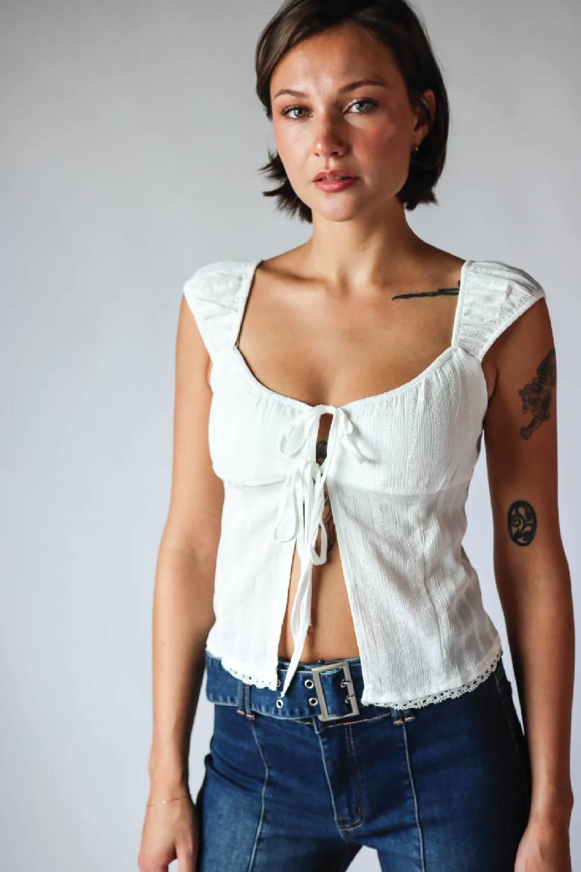 female model wearing white self-tie tank top and belted flare jeans