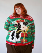 Plus-size green and red knit ugly Christmas sweater featuring an elf-hat wearing cow and gift box