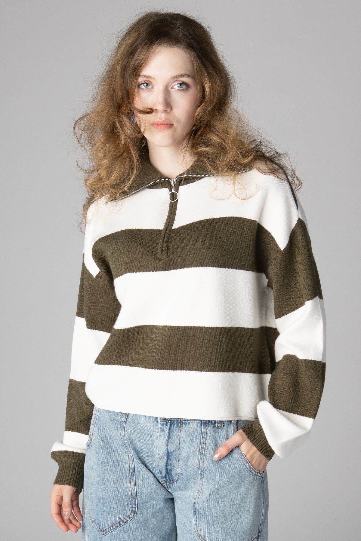 Woman wearing an olive green and white striped half-zip knit sweater