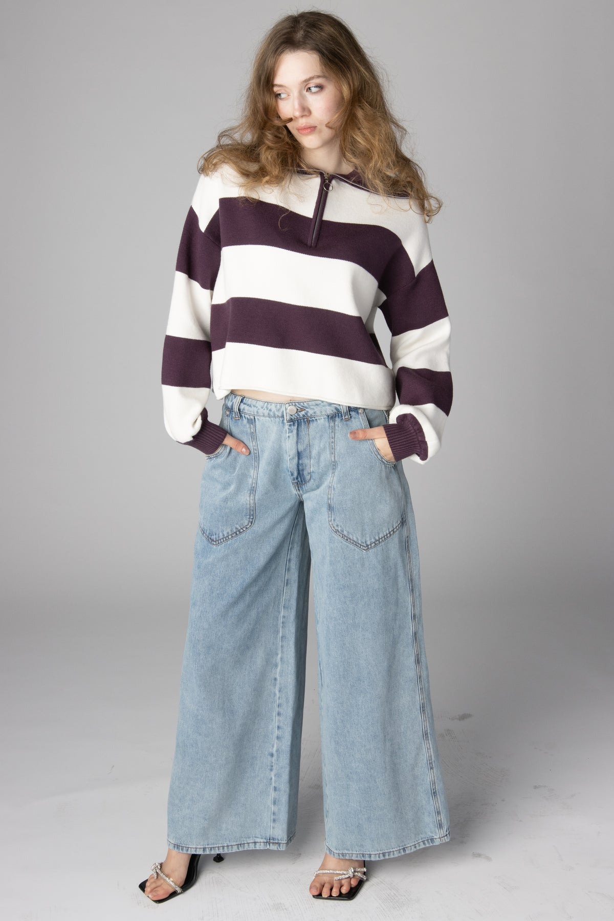 Woman wearing a maroon and cream striped half-zip cropped sweater with light-wash wide-leg