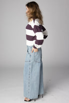 Woman wearing light wash wide-leg jeans and a purple and white striped sweater