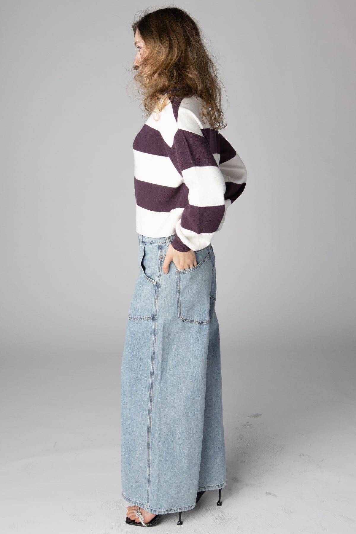 Woman wearing light wash wide-leg jeans and a purple and white striped sweater